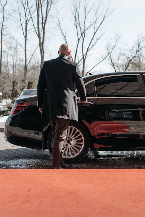 Professional chauffeur opening the door of a black luxury sedan in Toronto